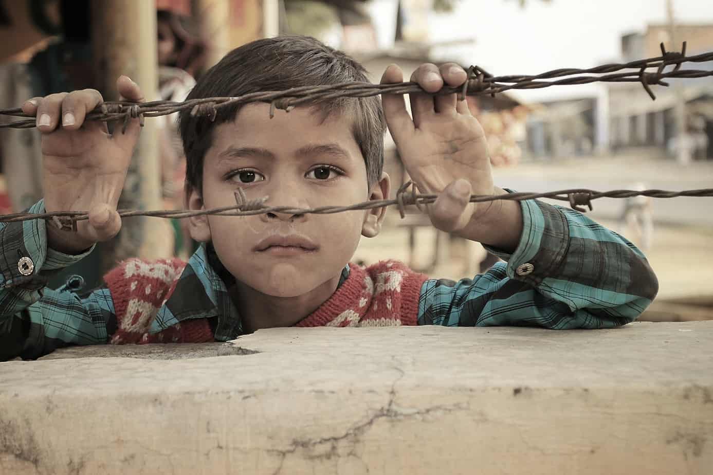 An Indian Child looking into barbwire fence