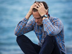 man in blue and brown plaid dress shirt touching his hair 897817