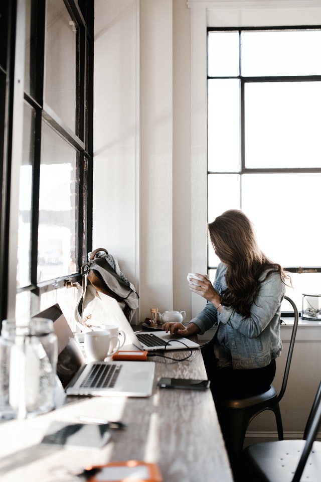 woman in gray jacket sitting beside desk 2682452