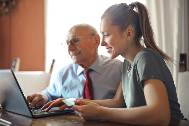 young woman helping senior man with payment on internet 3823488